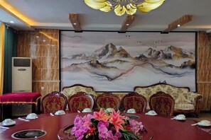 Une salle de conférence avec une table ronde, des chaises et un tableau représentant des montagnes accroché au mur.