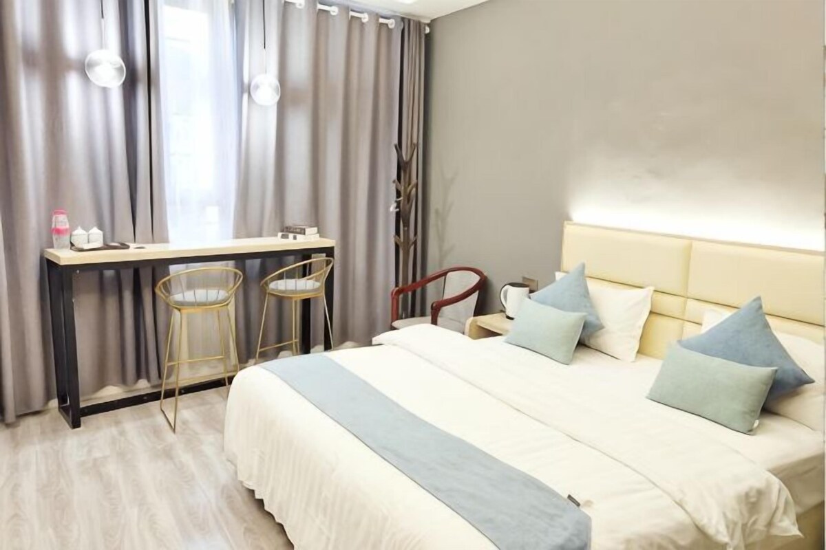 A hotel room with a bed, a desk, two chairs, and a nightstand.
