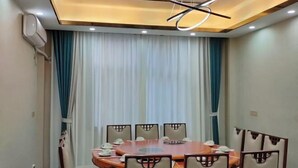 A conference room with a round table, six chairs, and a modern ceiling light fixture. - Shengcheng Jiayuan Hotel (Leishan)
