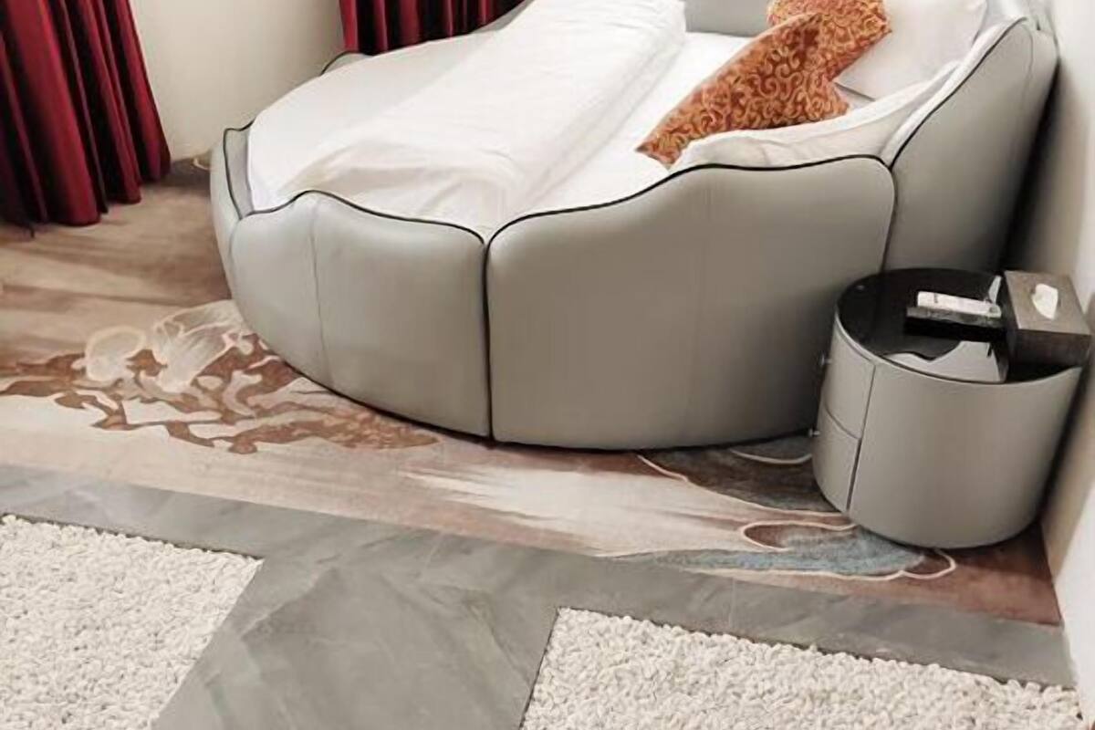 A modern living room with a curved sofa, a patterned throw pillow, a small side table, and a television.