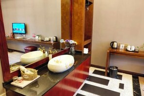 A hotel bathroom with a large mirror, two sinks, a television, and a wooden vanity with a vase of flowers. - Shengcheng Jiayuan Hotel (Leishan)