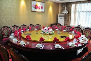 A conference room with a round table, chairs, and floral centerpieces. - Shengcheng Jiayuan Hotel (Leishan)