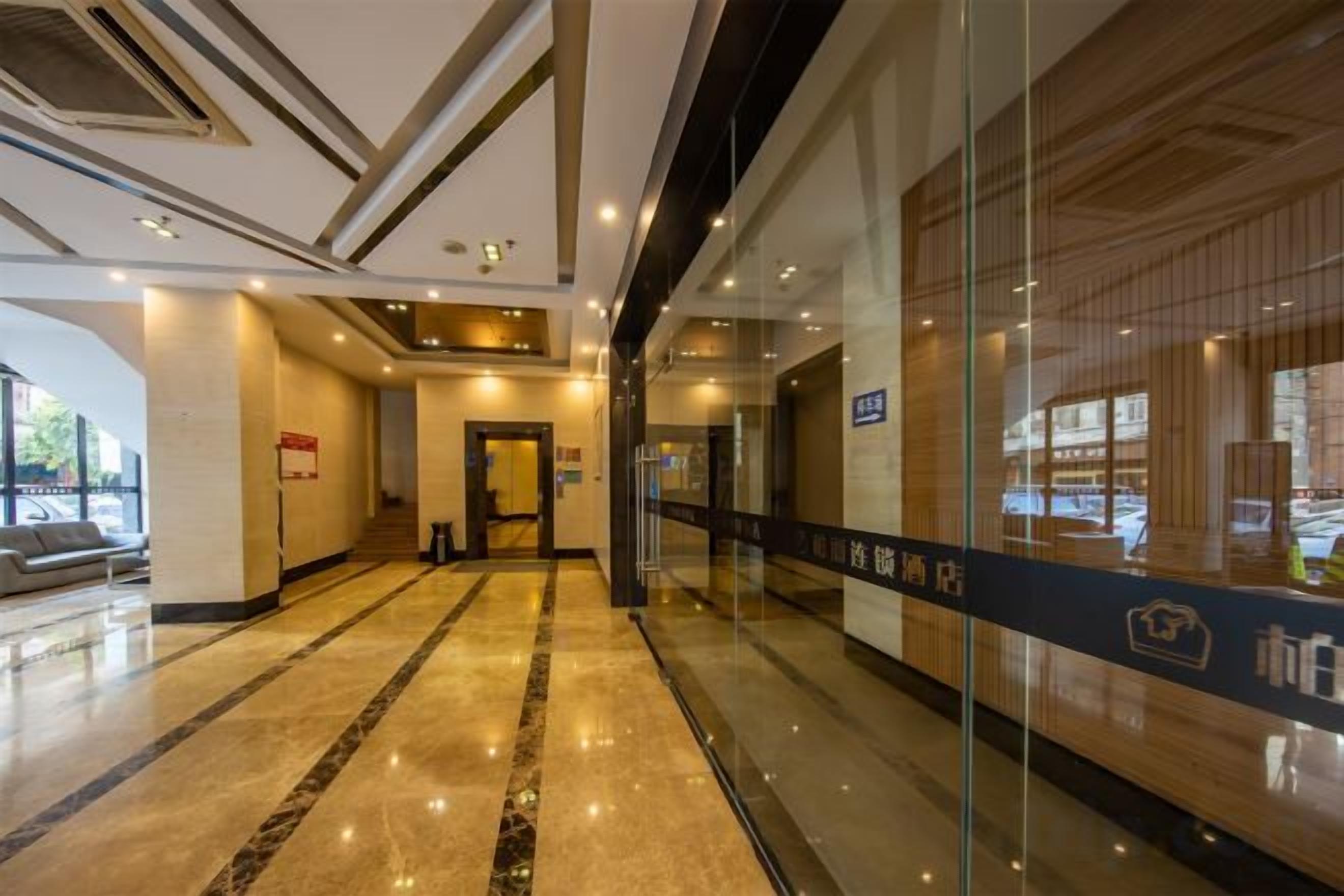 A hotel lobby with a marble floor, a reception desk, and a glass wall with a view.