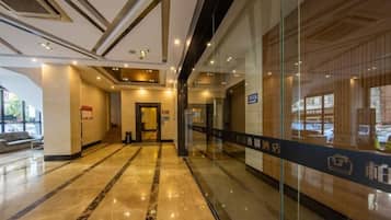 Um hall de hotel com piso de mármore, balcão de recepção e parede de vidro com vista.