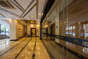 Un vestíbulo de hotel con piso de mármol, mostrador de recepción y pared de vidrio con vistas.