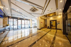 A hotel lobby with a marble floor, a reception desk, and a glass door entrance. - Park Lane Yiju Hotel (Jiangmen Taishan Pedestrian Street Pinghu Road) (Taishan)