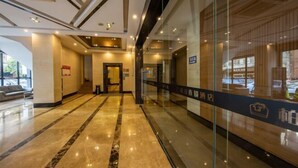 A hotel lobby with a marble floor, glass walls, and a reception desk. - Park Lane Yiju Hotel (Jiangmen Taishan Pedestrian Street Pinghu Road) (Taishan)