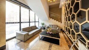 A modern living room with a sofa, coffee table, and a staircase with a geometric wall design. - Park Lane Yiju Hotel (Jiangmen Taishan Pedestrian Street Pinghu Road) (Taishan)