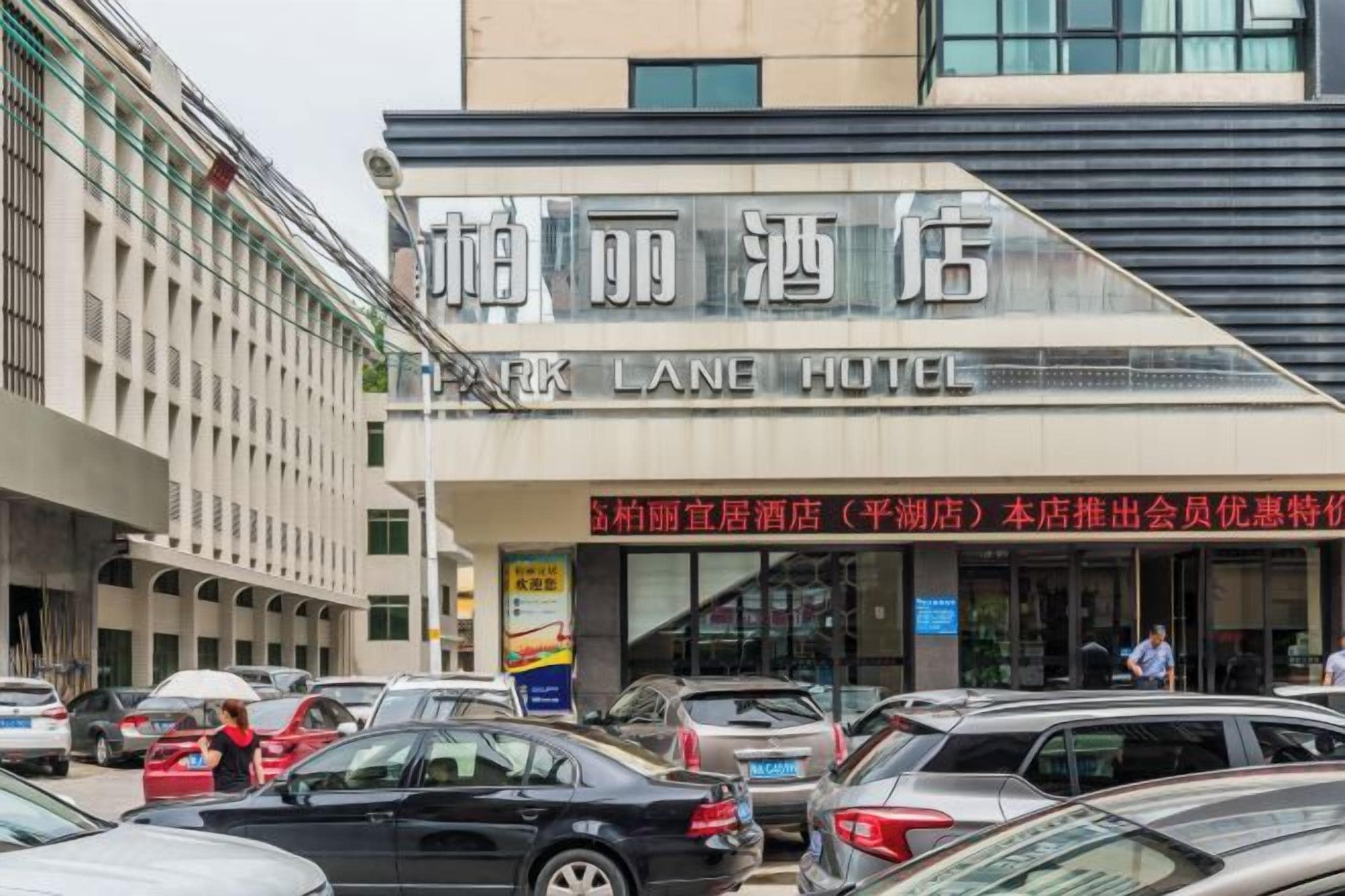 Entrada de un hotel con un letrero que dice 'Lane Hotel' y un estacionamiento con varios coches.