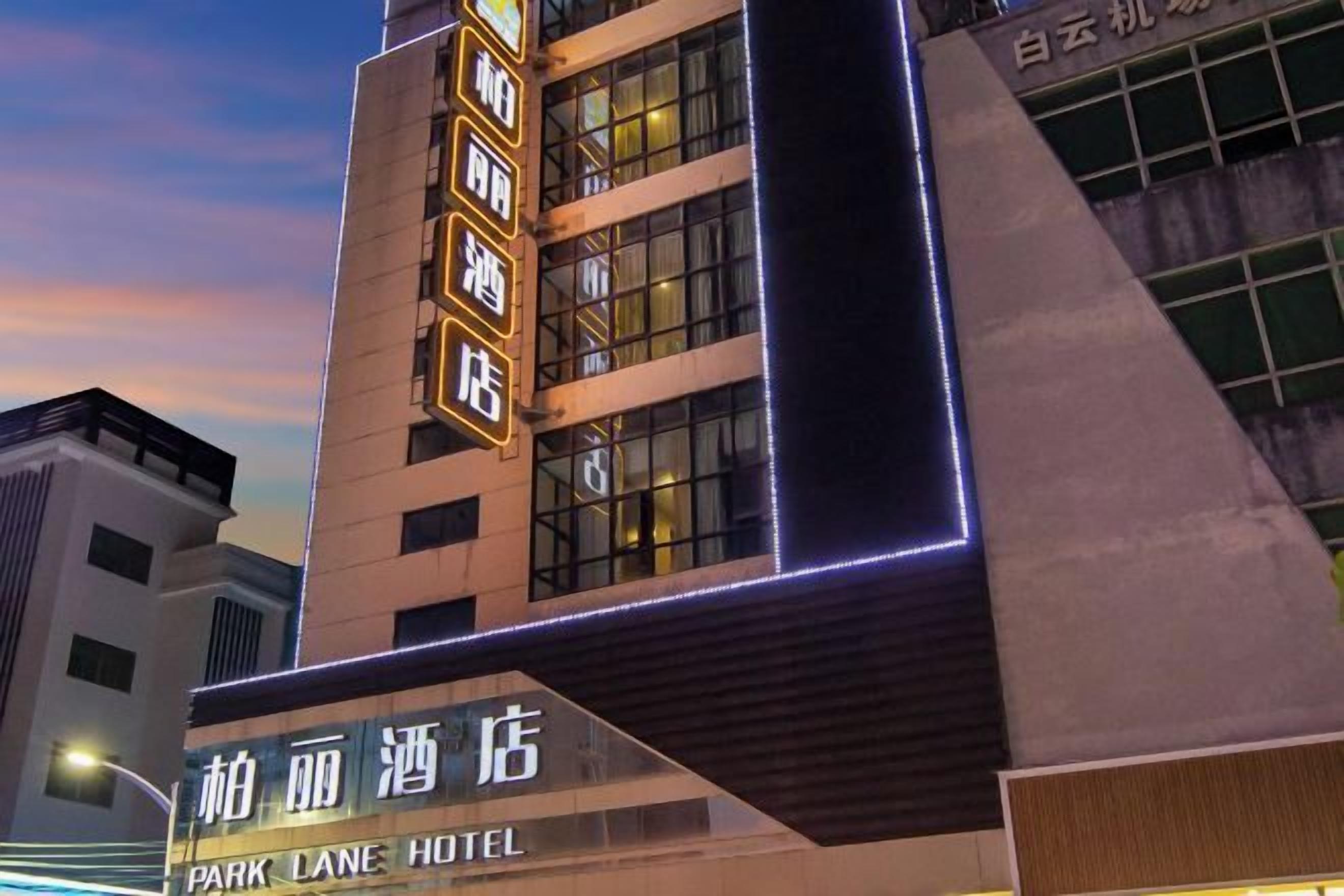 Un hotel con fachada moderna, que presenta señalización iluminada y una entrada destacada.