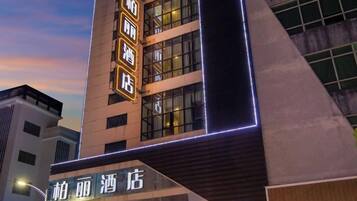 Un hotel con fachada moderna, que presenta señalización iluminada y una entrada destacada.