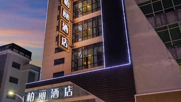 Un hotel con fachada moderna, señalización iluminada y una entrada destacada.
