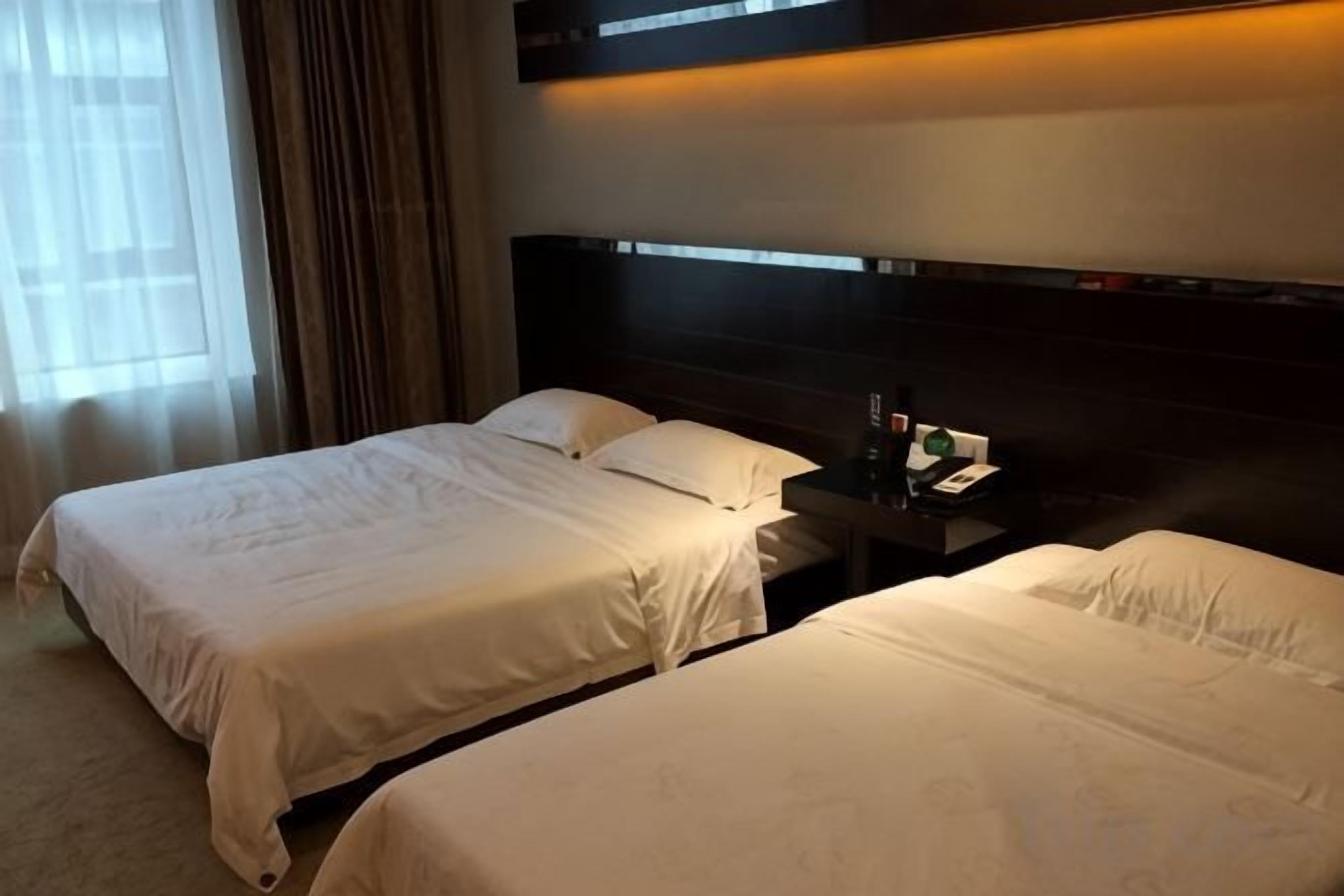 A hotel room with two beds, a nightstand, and a window with curtains.