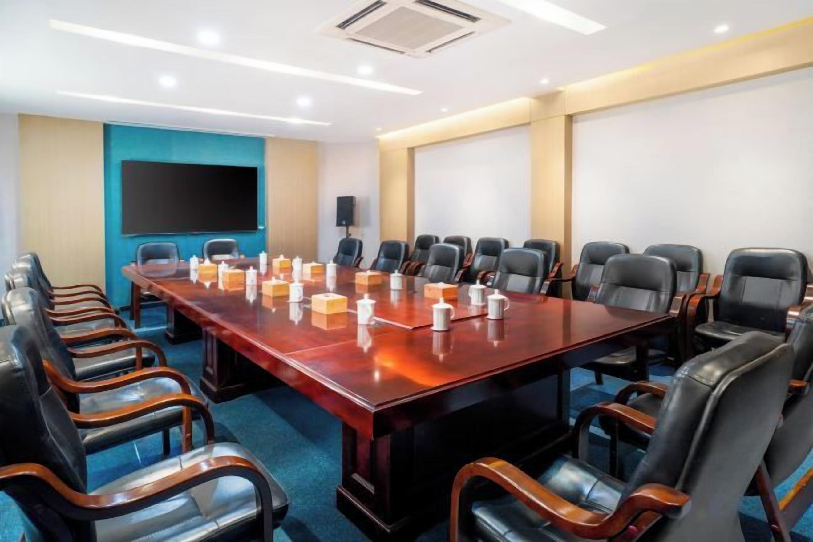 Un salón de conferencias con una mesa larga, varias sillas y una pantalla para proyector.