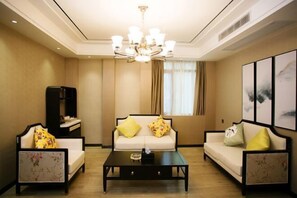 A living room with a sofa set, a coffee table, a bookshelf, and a chandelier. - Yunlong Hotel (Zhuxi)