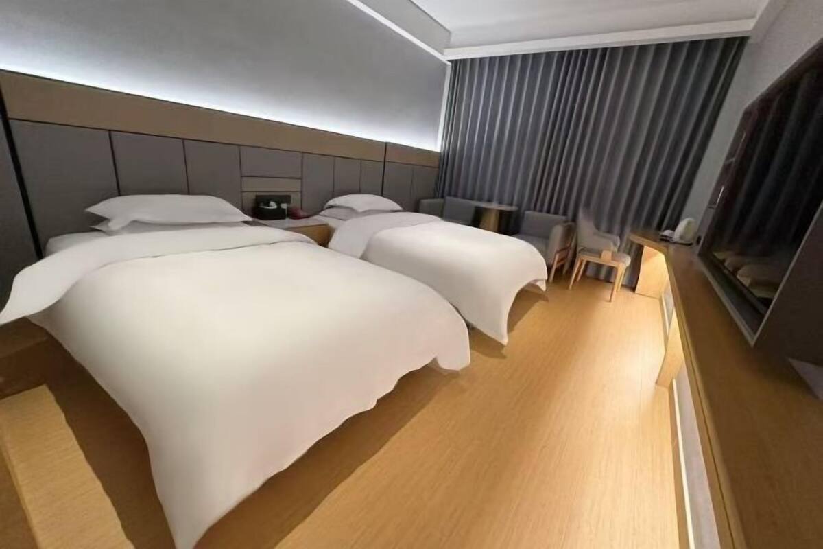 A modern hotel room with two beds, a desk, and a chair.