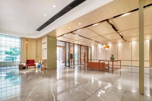 A spacious lobby with a polished marble floor, a reception desk, and a seating area with a red sofa. - Yunlong Hotel (Zhuxi)