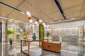 A modern hotel lobby with a wooden reception desk, a white bench, and a glass partition. - Yunlong Hotel (Zhuxi)