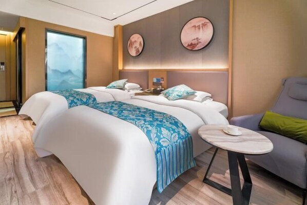 A hotel room with a bed, a small table, a chair, and artwork on the walls. - Yunlong Hotel (Zhuxi)