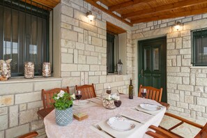 Enjoy meals in this beautifully appointed dining area with a stone wall backdrop, wooden ceiling, and comfortable seating for all.