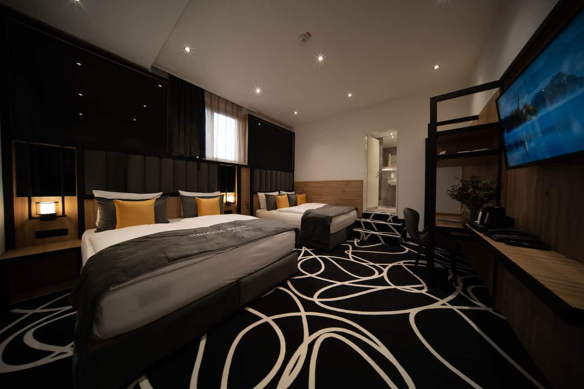 Une chambre d’hôtel avec un grand lit, un lit plus petit, un bureau et une télévision.
