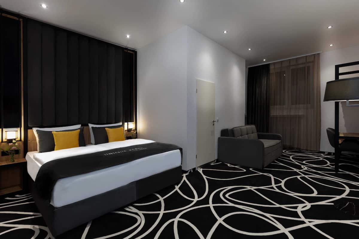 Une chambre d’hôtel moderne dotée d’un grand lit, d’un coin salon et d’un bureau.