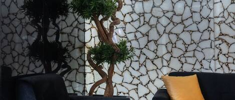 Una habitación con un sofá negro, un cojín amarillo y una pared con textura de piedra agrietada.