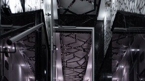 Un interior moderno con una pared de diseño geométrico y una escalera que sube.