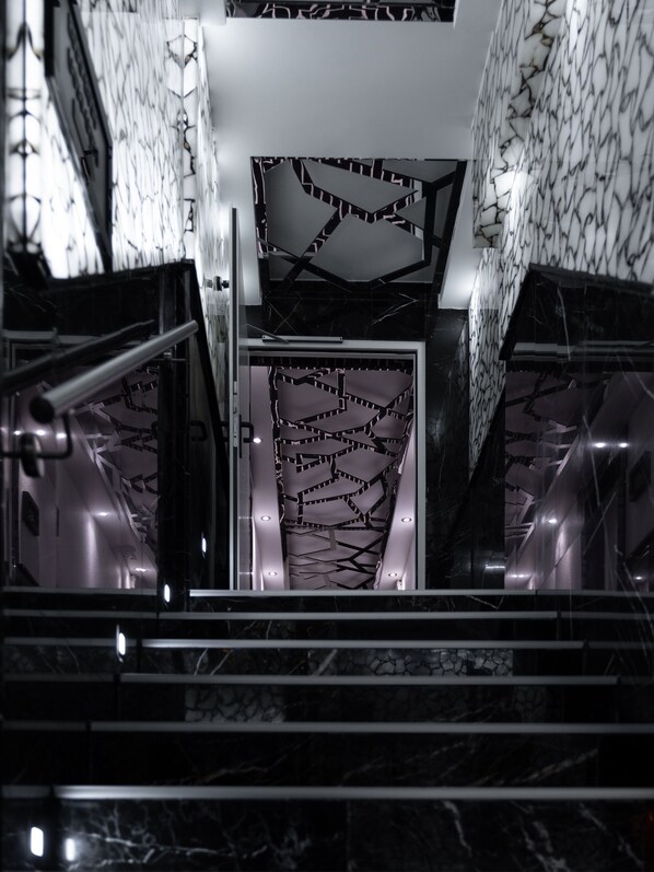 A modern interior with a geometric patterned wall and a staircase leading upwards. - Hotel Pearl Dortmund-Nordstadt (Dortmund)