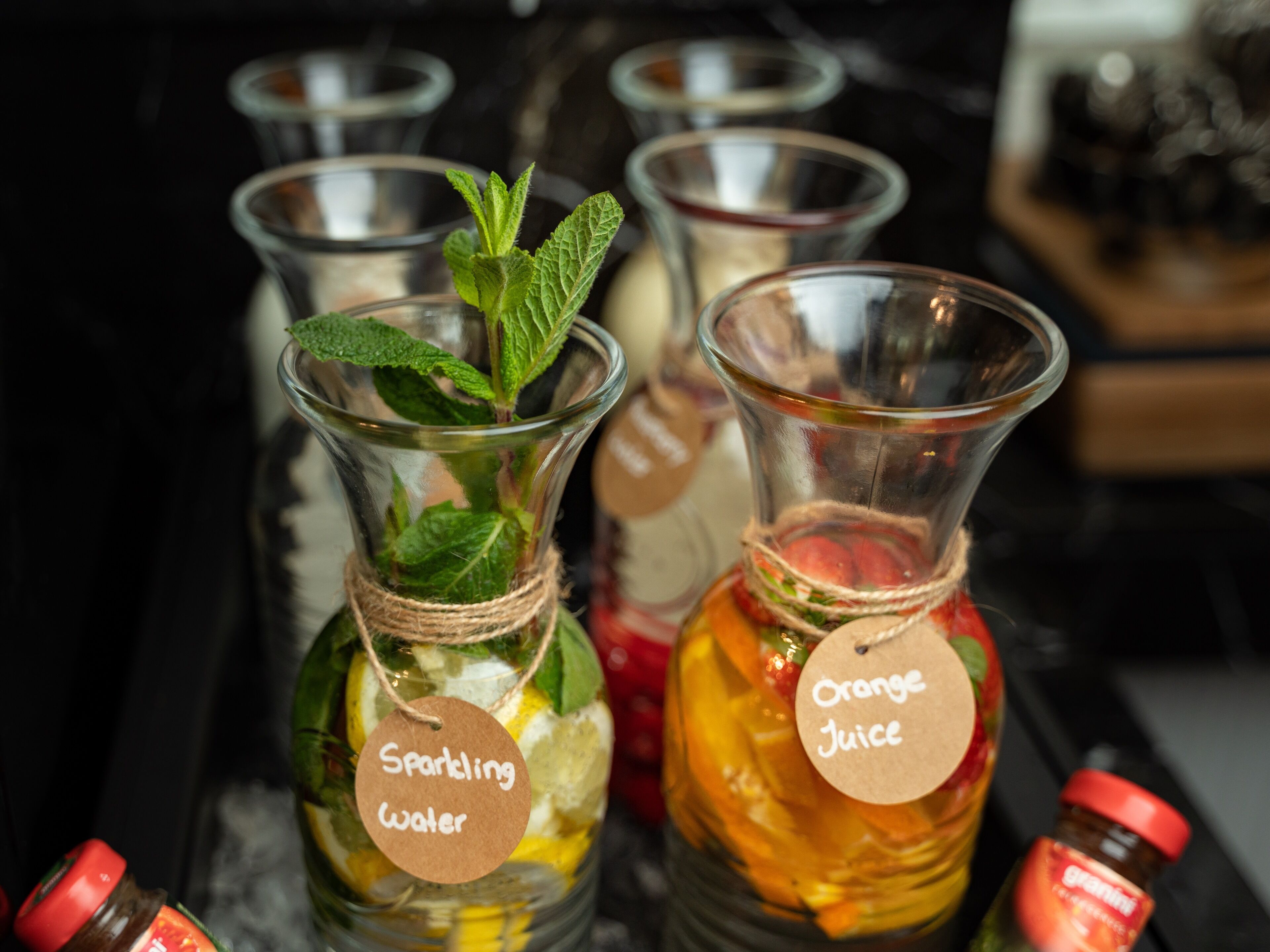 Trois bouteilles en verre, toutes munies d’une étiquette : l’une indique « eau gazeuse » et l’autre « jus d’orange ».