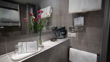Un baño moderno con un gorro de ducha, un secador de pelo y un florero con flores en la encimera.