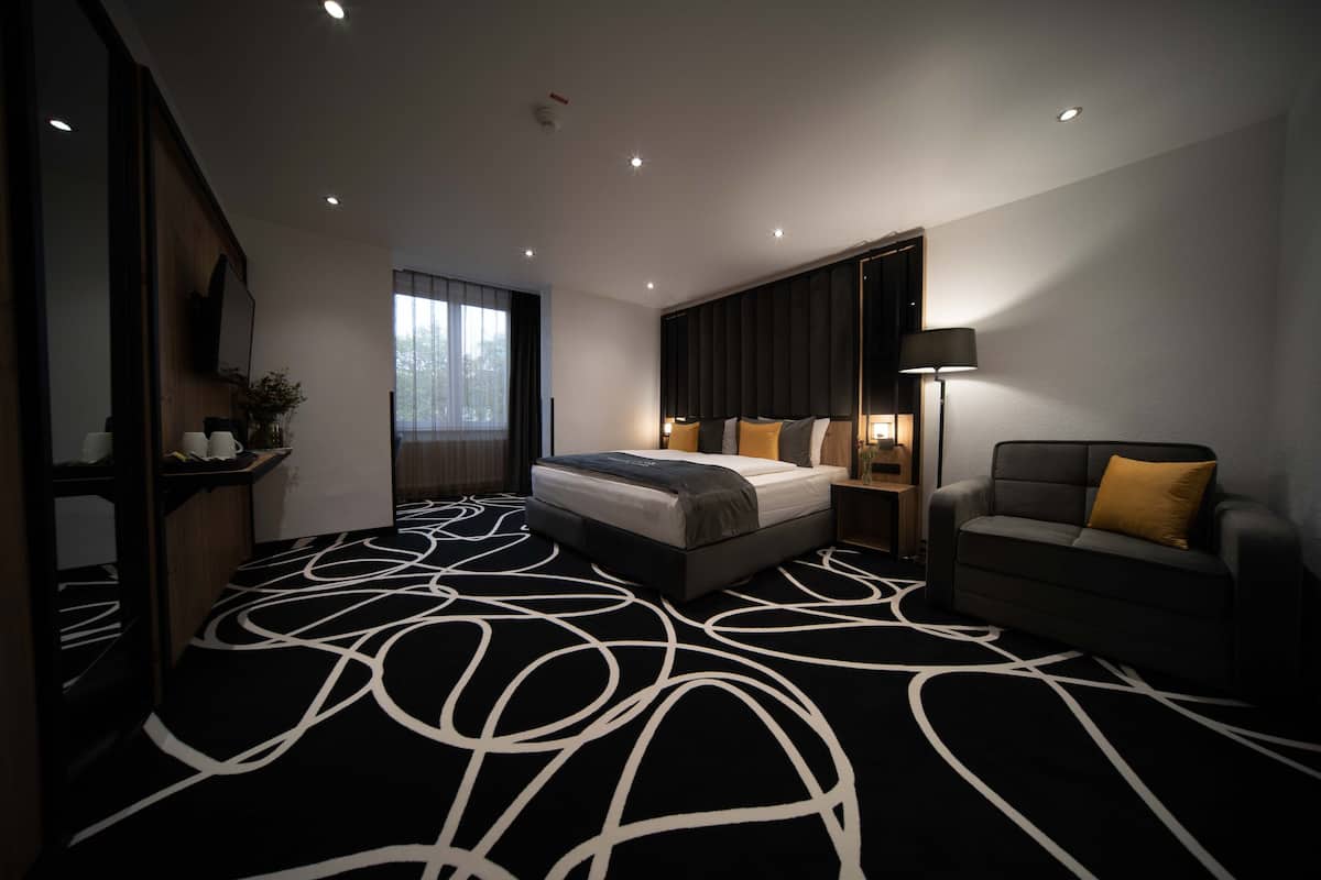 Une chambre d’hôtel moderne avec un grand lit, un canapé et un bureau.