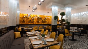 Un restaurante con pared de mármol, sillas amarillas y una larga mesa de comedor.