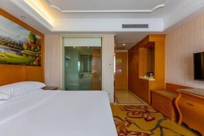 A hotel room with a bed, a painting on the wall, a television, a wooden dresser, and a carpeted floor. - Vienna Hotel (Xinhua South Store, Hankou North Road, Wuhan) (Wuhan)