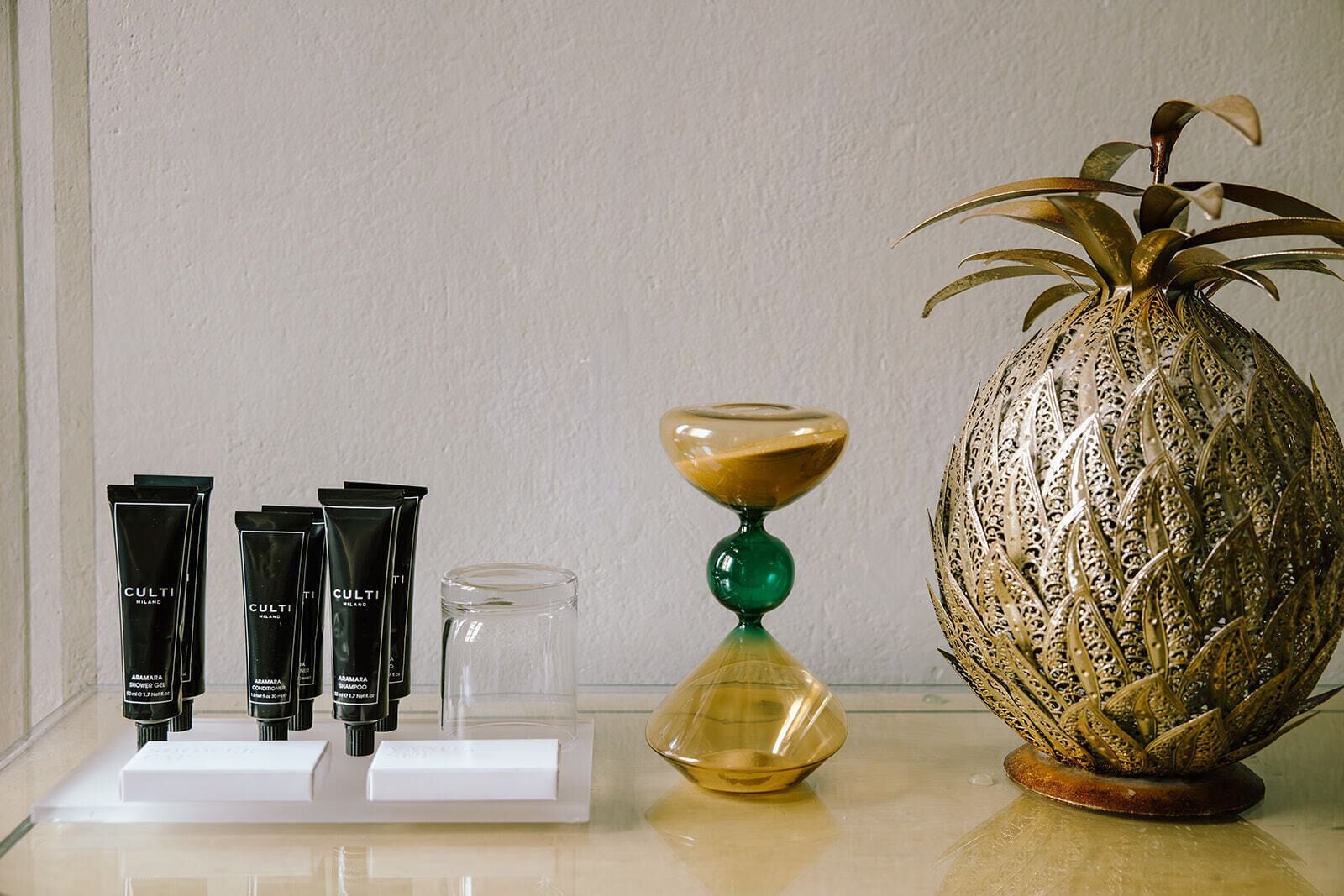 Een badkamermeubel met toiletartikelen, een glazen pot en een decoratieve vaas.