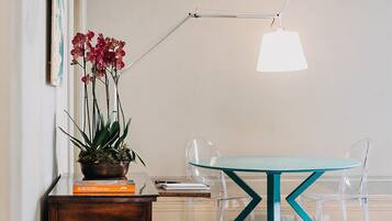 A modern interior with a wooden sideboard, a glass table with teal legs, and a clear chair.