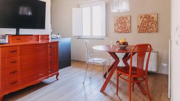 Une cuisine moderne avec des meubles de rangement rouges, une table à manger avec des chaises et un téléviseur fixé au mur.