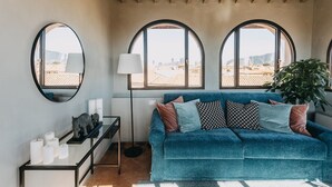 A cozy room with a blue sofa, three arched windows, a floor lamp, a plant, and a small table with candles. - Palazzo Feroci (Pisa)
