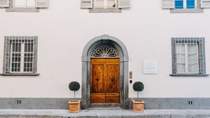 A building with a wooden door, two potted plants, and a plaque on the wall. - Palazzo Feroci (Pisa)