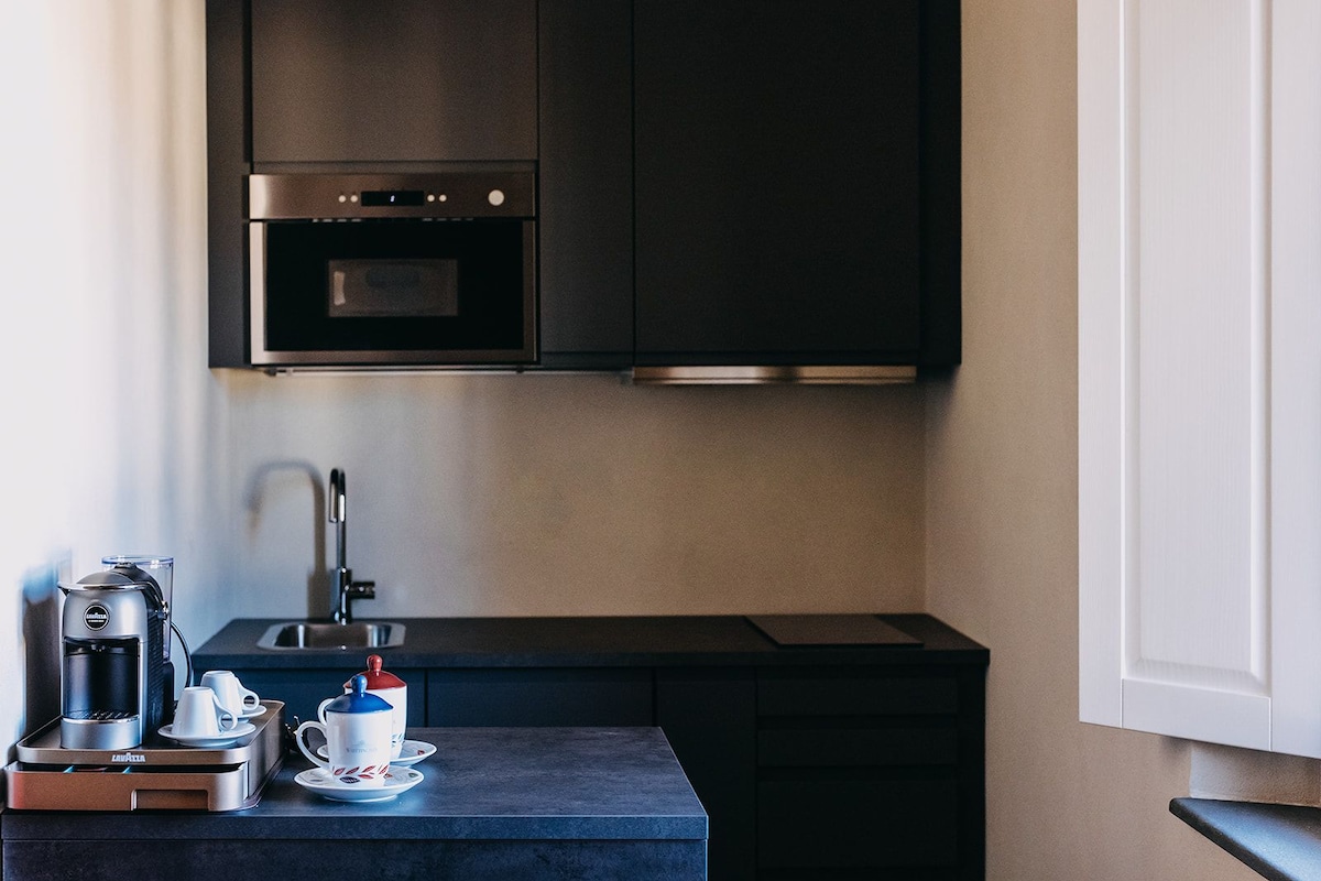 A compact kitchen with a built-in oven, a coffee machine, and a small sink.
