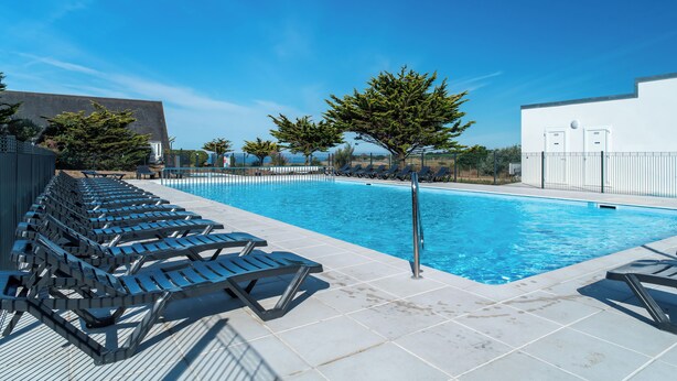 A swimming pool with lounge chairs and a tree.