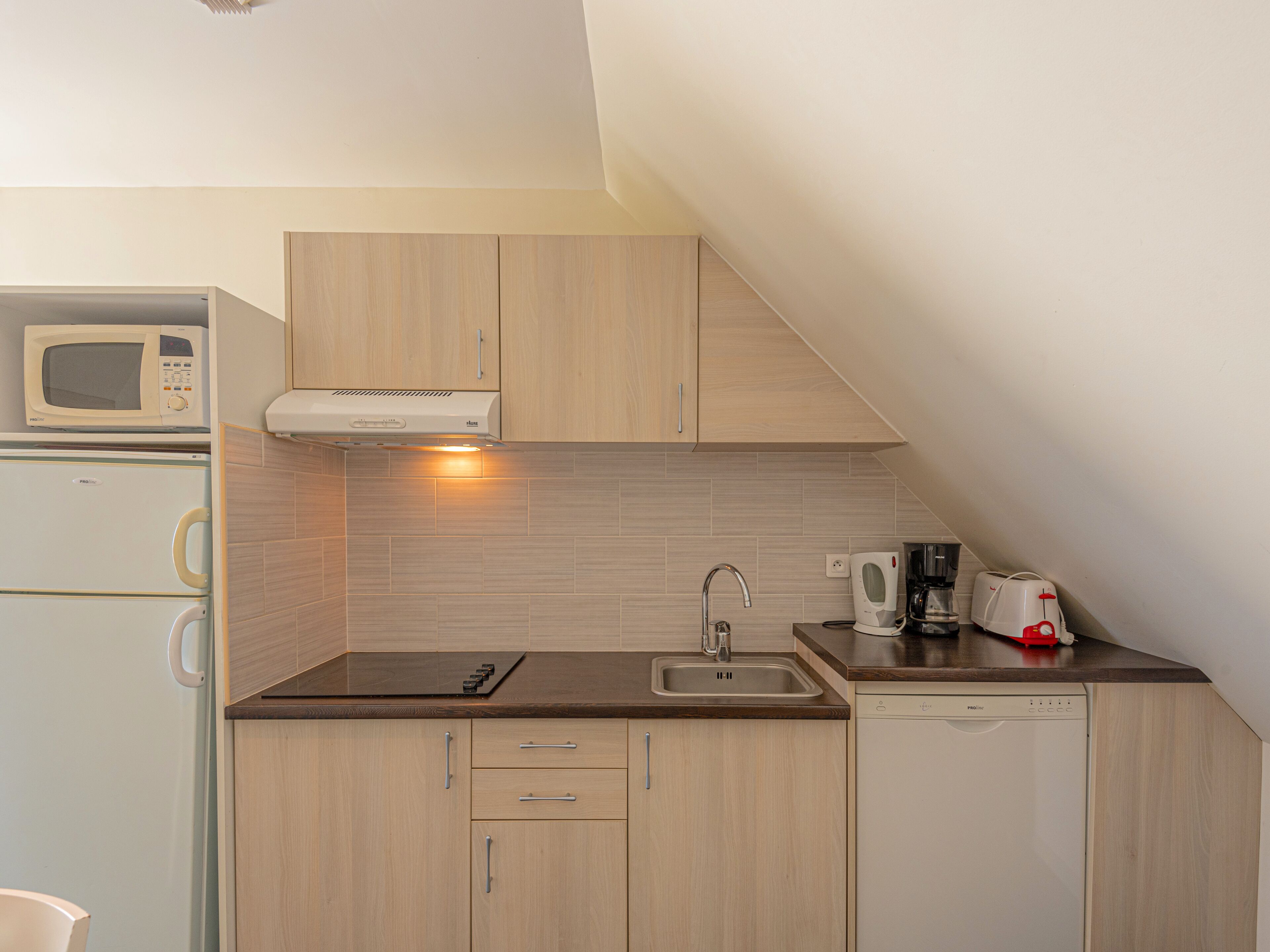 A compact kitchen with a microwave, toaster, and dishwasher.
