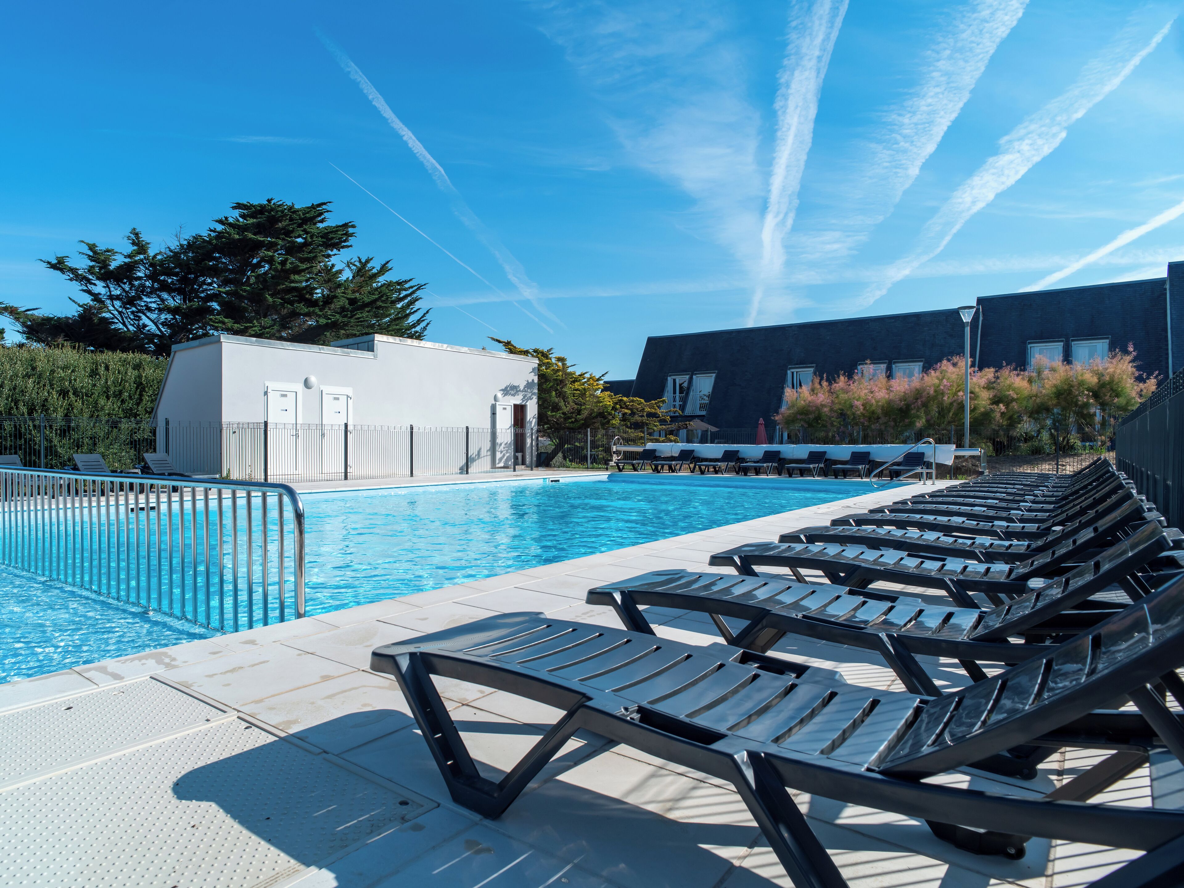 A swimming pool with lounge chairs and a building in the background.