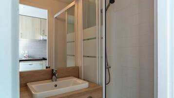 Un bagno moderno con un mobile bagno in legno, un lavandino bianco e una cabina doccia in vetro.