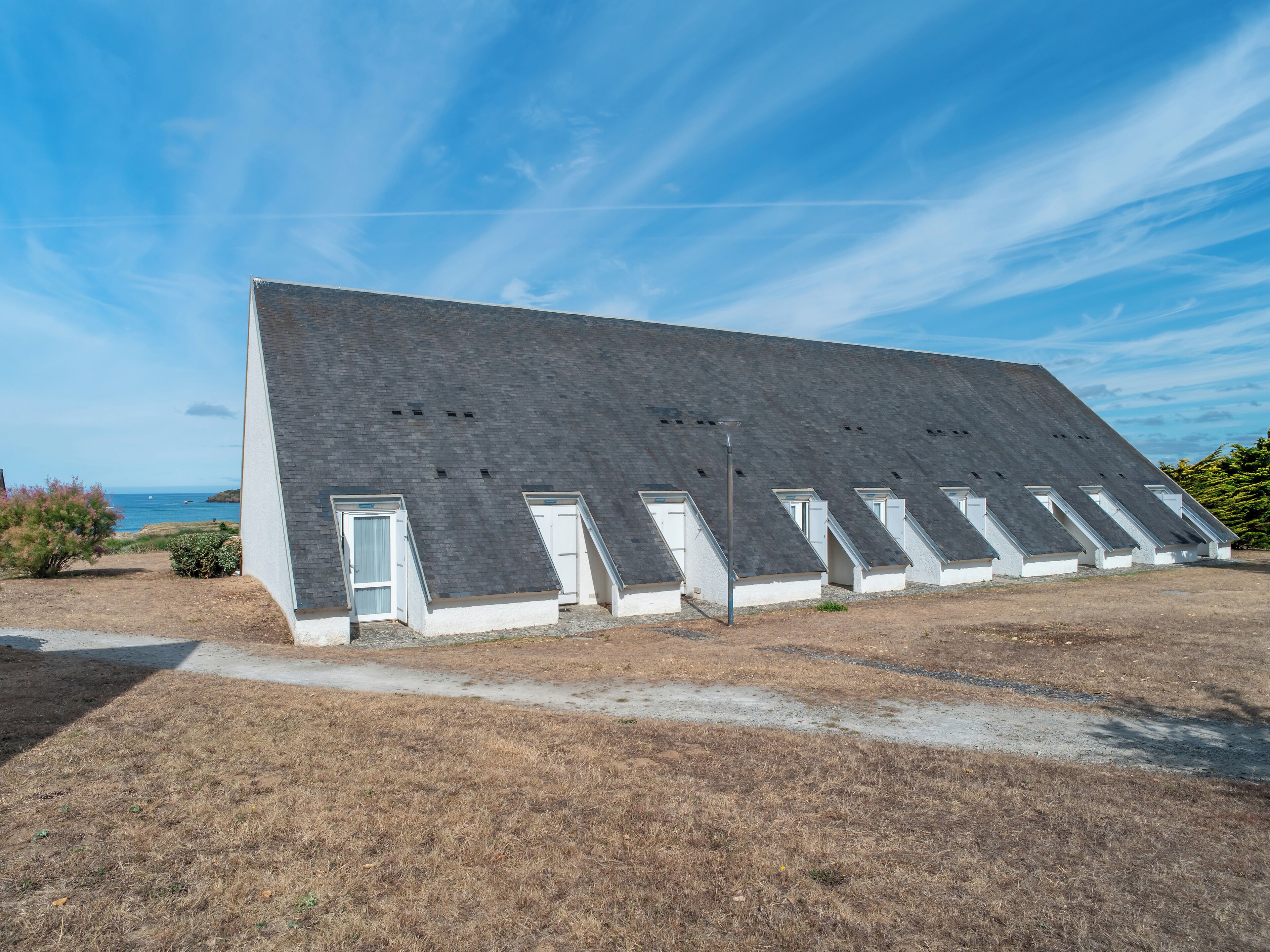 Un bâtiment moderne doté d’un toit en pente et de plusieurs fenêtres en lucarne.