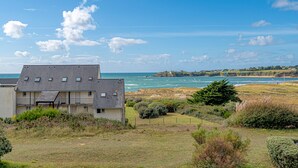 A coastal property with a large house, a grassy yard, and a view of the sea.