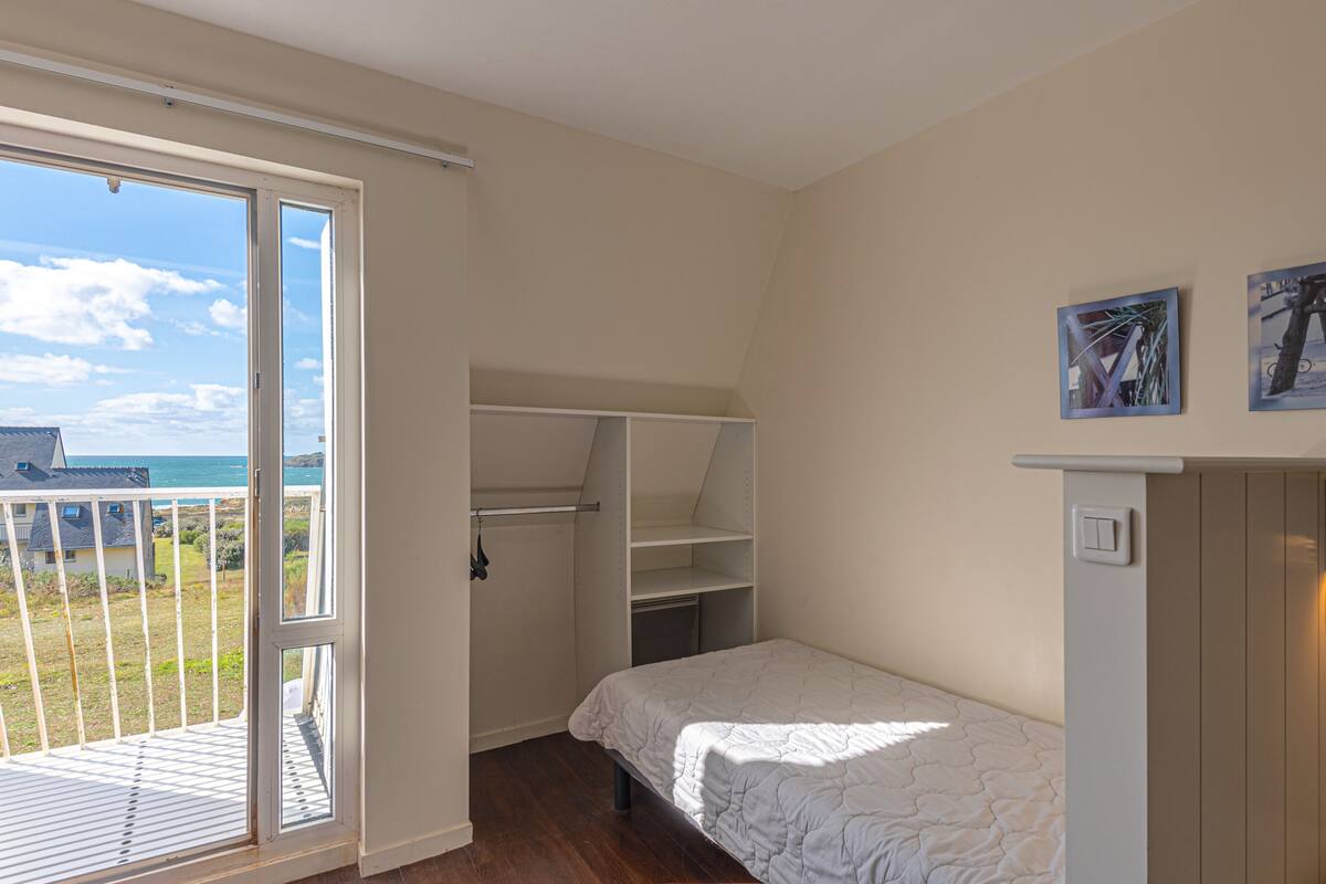 Un dormitorio con cama, armario y vista al mar.