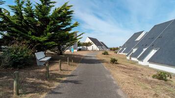 Un chemin mène à une rangée de bâtiments modernes, coiffés de toits blancs, sous un ciel dégagé.