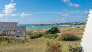 A coastal view with a building in the foreground and a beach in the background.