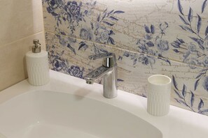 Bathroom features a large oval-shaped bathtub, modern faucet, and decorative floral tile design.